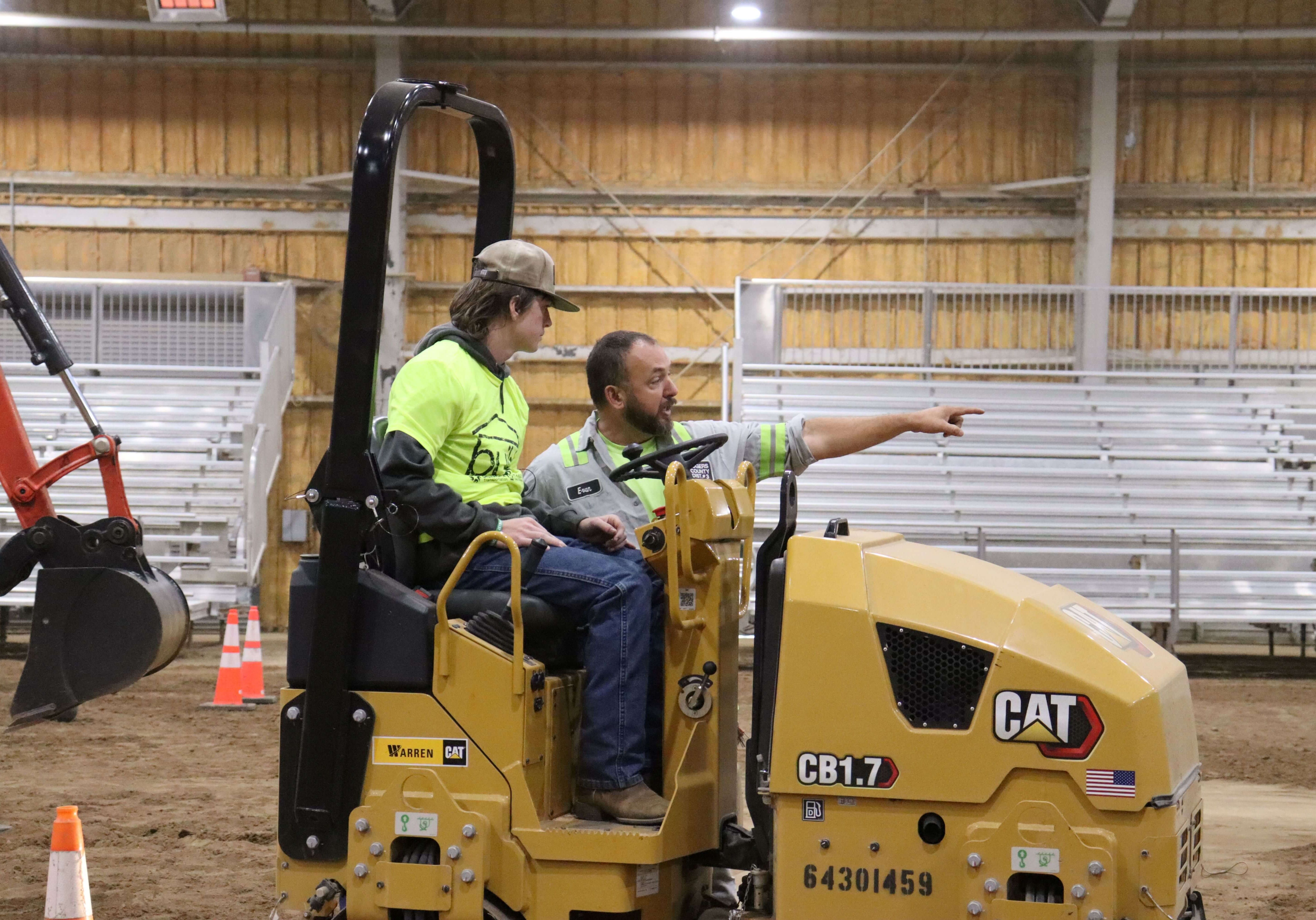 student driving heavy machine with instructor pointing the way